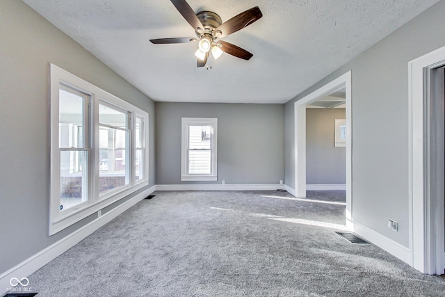 spare room featuring baseboards, a ceiling fan, visible vents, and carpet