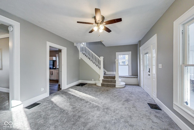 entryway with carpet flooring, visible vents, baseboards, stairway, and a ceiling fan