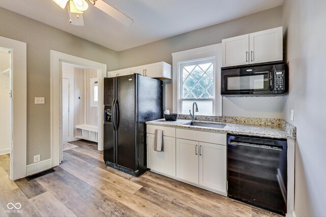kitchen featuring a sink, white cabinets, black appliances, and light stone counters