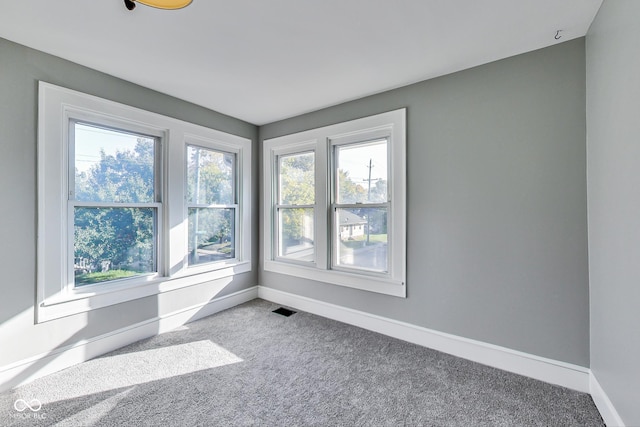 carpeted spare room featuring baseboards and visible vents
