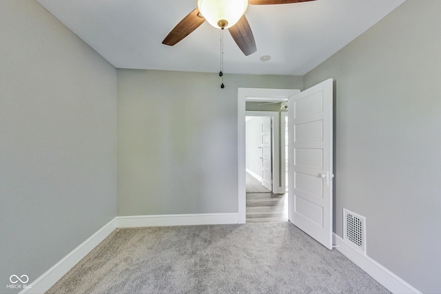 carpeted empty room featuring baseboards, visible vents, and a ceiling fan