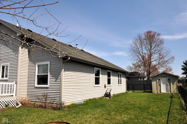 view of home's exterior featuring a shed, fence, an outdoor structure, and a lawn