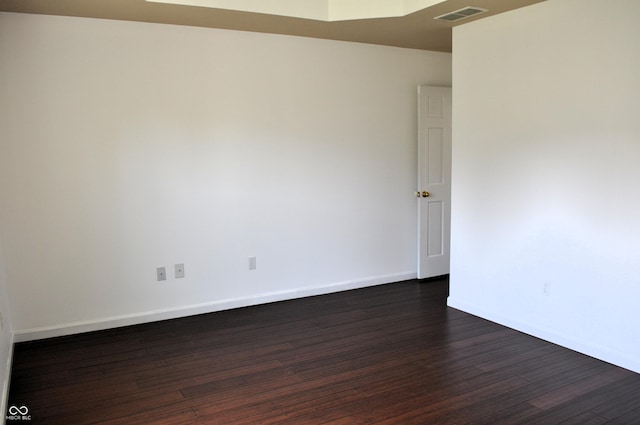 spare room featuring visible vents, baseboards, and dark wood-style floors