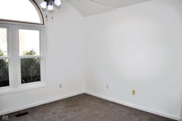 empty room featuring visible vents, baseboards, dark carpet, ceiling fan, and vaulted ceiling