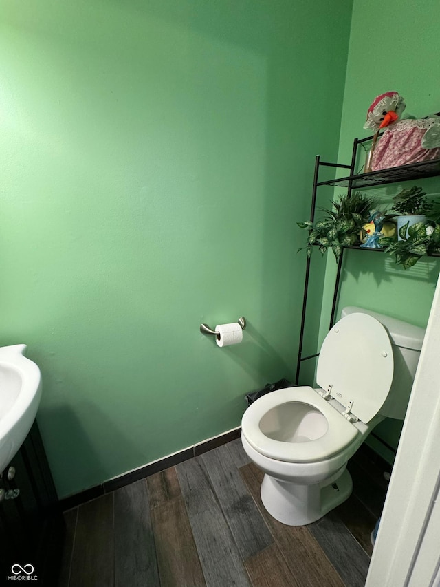 bathroom with toilet, wood finished floors, and baseboards