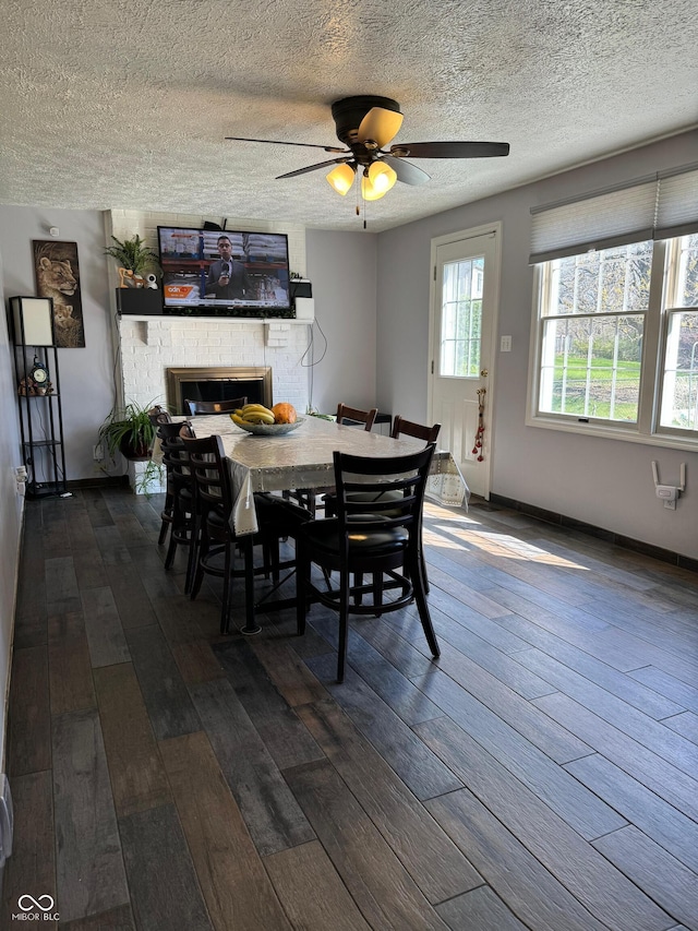 dining space with a fireplace, dark wood-style flooring, a textured ceiling, and ceiling fan