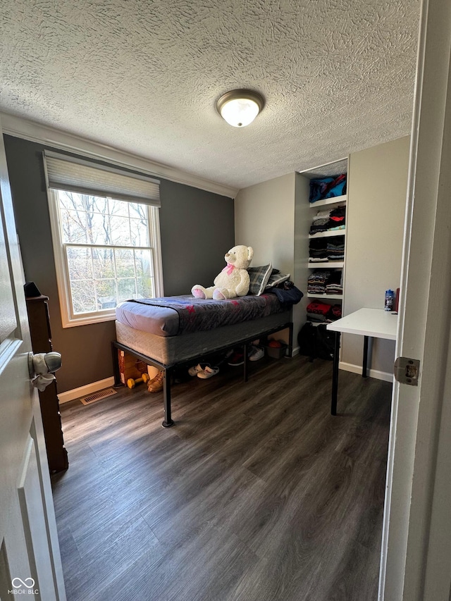 bedroom with a textured ceiling, baseboards, and dark wood finished floors