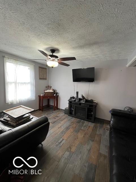 living room with a ceiling fan, wood finished floors, and a textured ceiling