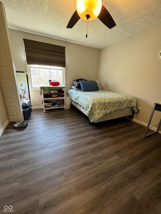 bedroom featuring baseboards, a ceiling fan, wood finished floors, and a textured ceiling