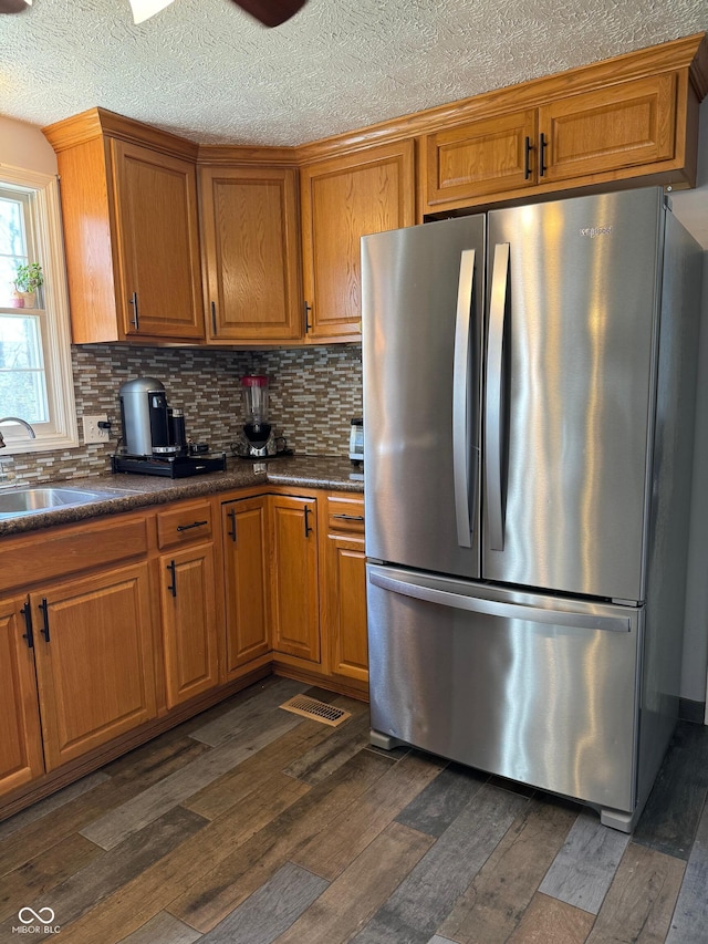 kitchen with brown cabinets, dark wood-style floors, a sink, and freestanding refrigerator