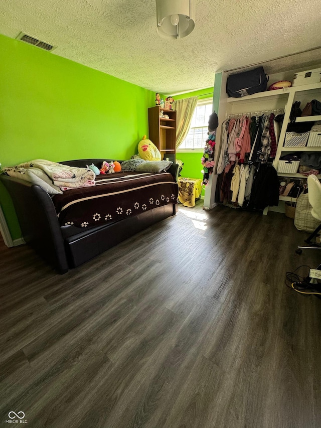 bedroom featuring visible vents, a closet, wood finished floors, and a textured ceiling