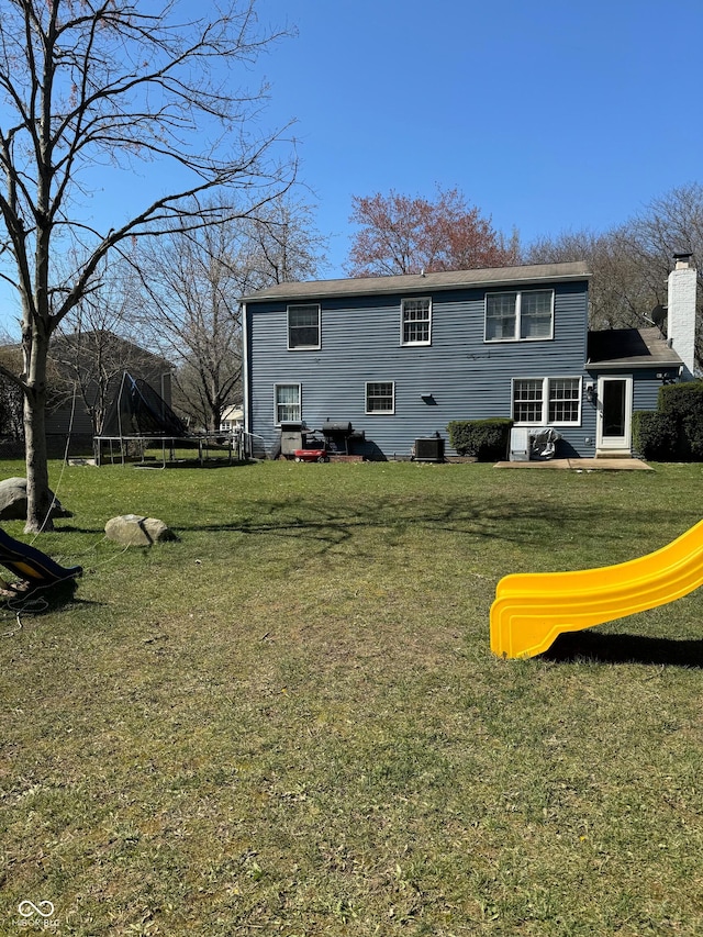 back of property featuring central air condition unit, a yard, and a chimney