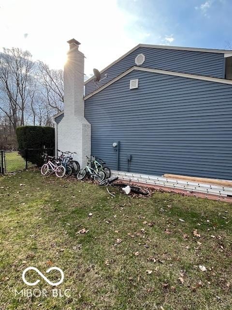 view of side of home featuring fence and a lawn