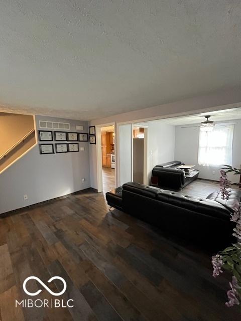 living area featuring visible vents, a textured ceiling, stairway, and dark wood-style floors