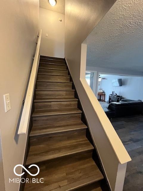stairs with a textured ceiling and wood finished floors