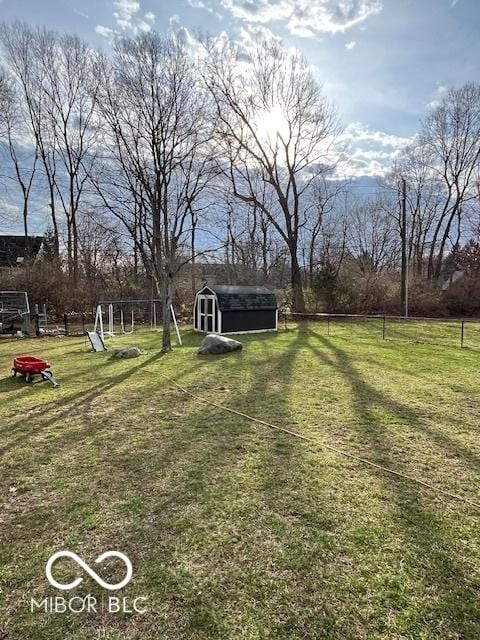 view of yard featuring a storage shed, an outbuilding, and fence