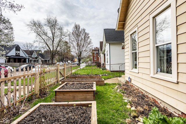 view of yard featuring a vegetable garden, fence, and a residential view