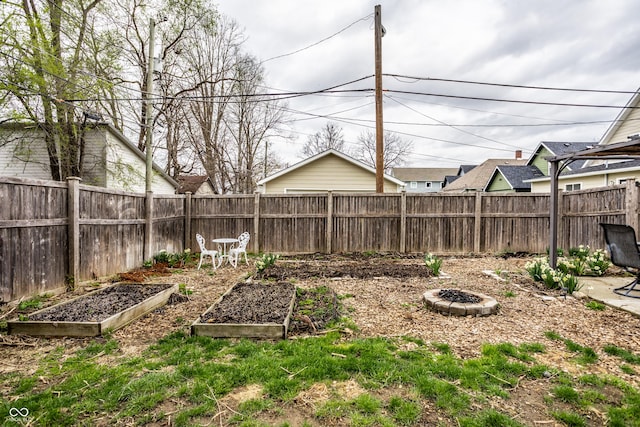 view of yard with a fenced backyard, an outdoor fire pit, and a vegetable garden