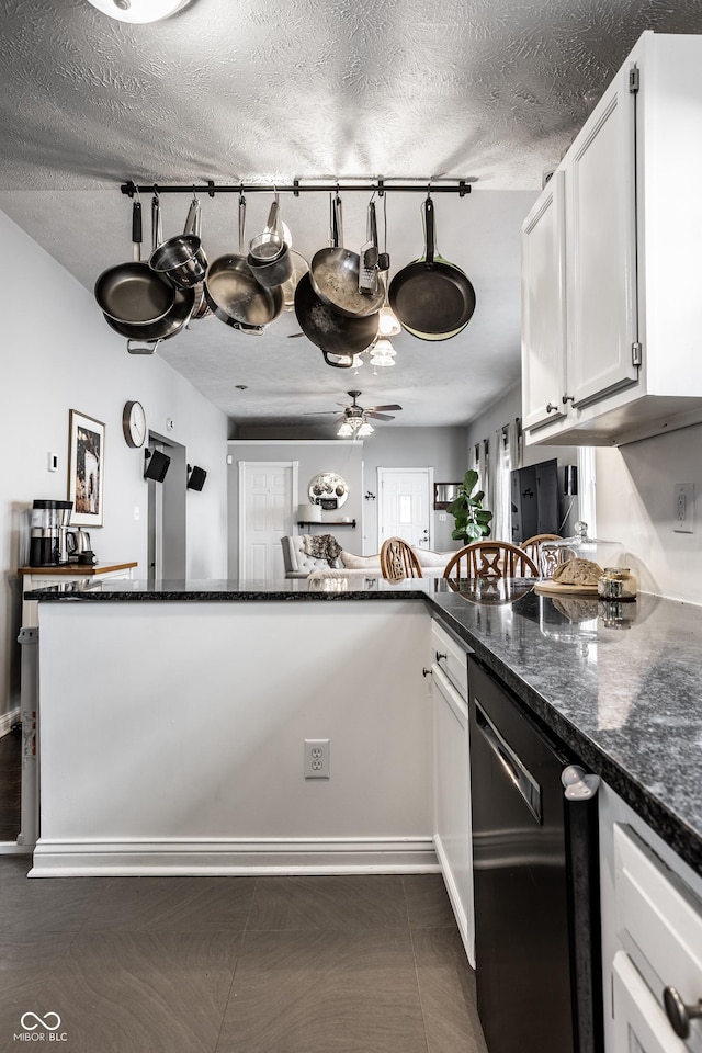 kitchen with a textured ceiling, dishwashing machine, dark stone countertops, white cabinets, and ceiling fan