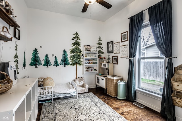 sitting room featuring dark wood-type flooring, baseboards, a healthy amount of sunlight, and a ceiling fan