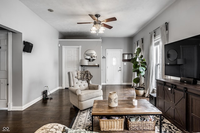 living area featuring baseboards, dark wood-style floors, and a ceiling fan
