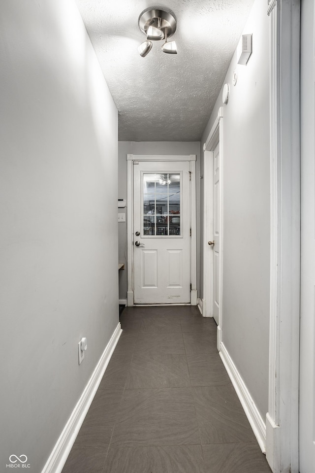 hall featuring baseboards and a textured ceiling