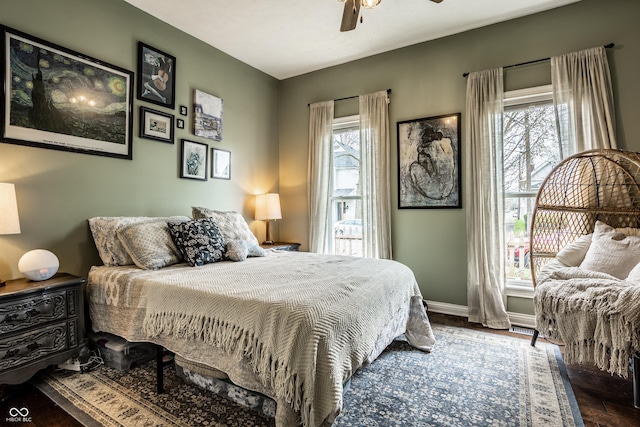 bedroom with multiple windows, wood finished floors, ceiling fan, and baseboards