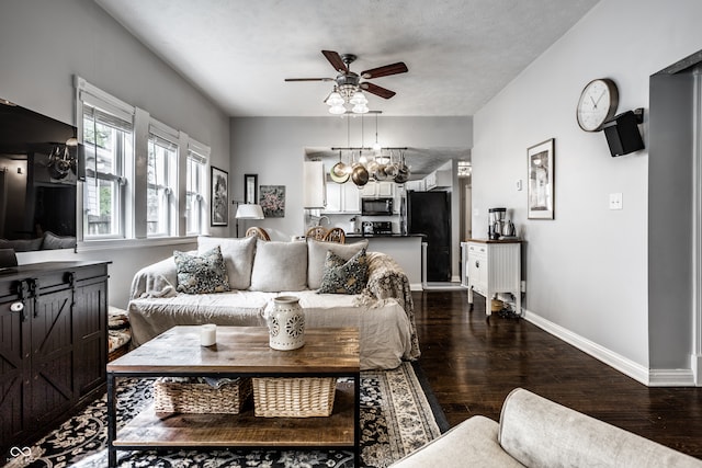 living room featuring dark wood-type flooring, baseboards, and a ceiling fan