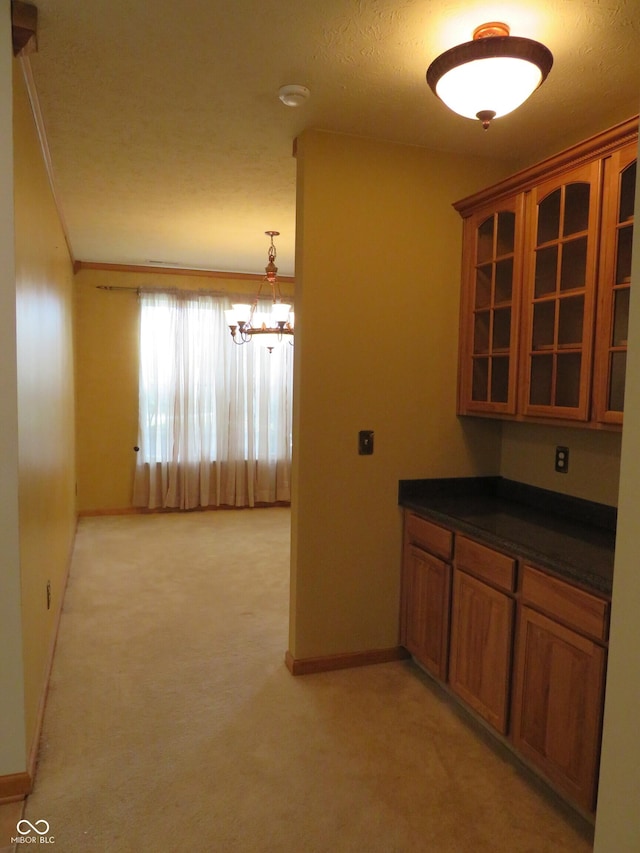 8358 Balmoral Dr, Avon, IN 46123 - kitchen with brown cabinets, dark countertops, light colored carpet, glass insert cabinets, and a chandelier