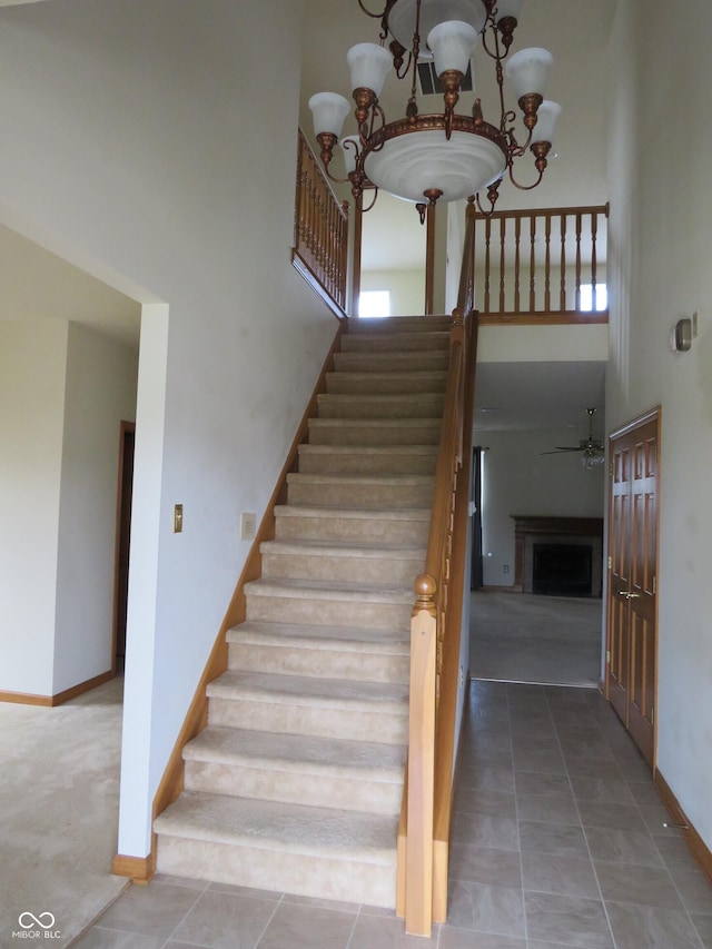 8358 Balmoral Dr, Avon, IN 46123 - stairs featuring a high ceiling, a chandelier, a ceiling fan, a fireplace, and tile patterned flooring