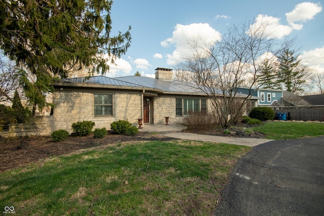 7525 N Meridian St, Indianapolis, IN 46260 - view of front of home featuring a standing seam roof, metal roof, stone siding, a front lawn, and a chimney