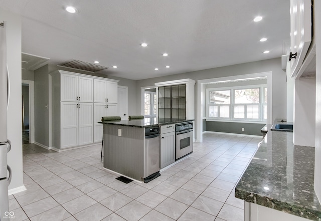 7525 N Meridian St, Indianapolis, IN 46260 - kitchen featuring light tile patterned flooring, dark stone countertops, white cabinets, recessed lighting, and oven
