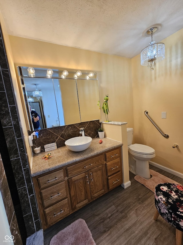 bathroom with toilet, vanity, wood finished floors, and a textured ceiling
