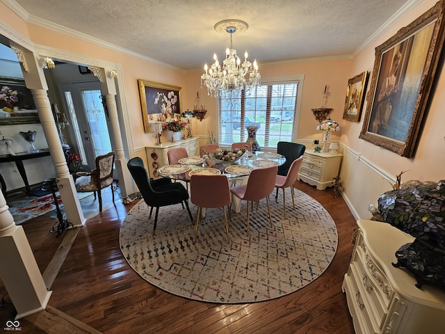 dining area featuring ornamental molding, a textured ceiling, an inviting chandelier, and dark wood finished floors