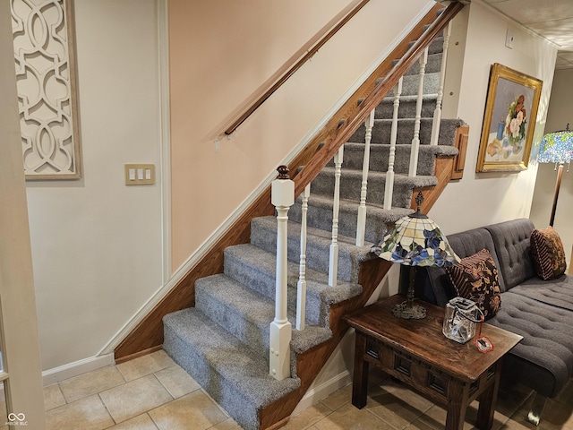 stairway with tile patterned floors and baseboards