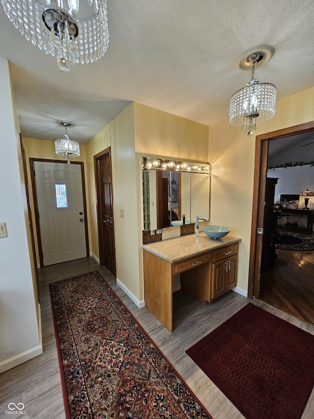 bathroom with a sink, baseboards, a chandelier, and wood finished floors