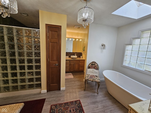 bathroom with a freestanding tub, an inviting chandelier, a stall shower, and wood finished floors