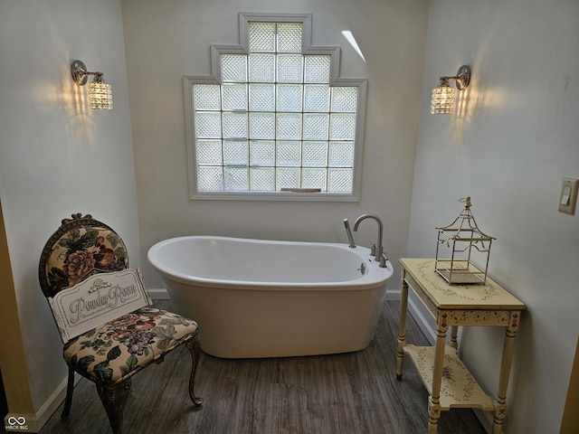 full bath with a freestanding bath, baseboards, and wood finished floors