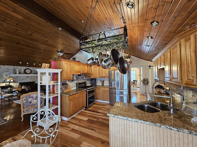 kitchen featuring stone countertops, a sink, stainless steel appliances, light wood finished floors, and decorative backsplash