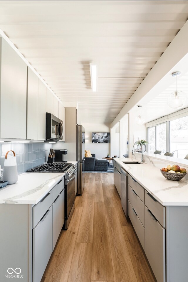 1802 Bellefontaine St, Indianapolis, IN 46202 - kitchen featuring appliances with stainless steel finishes, a sink, light wood-type flooring, backsplash, and modern cabinets