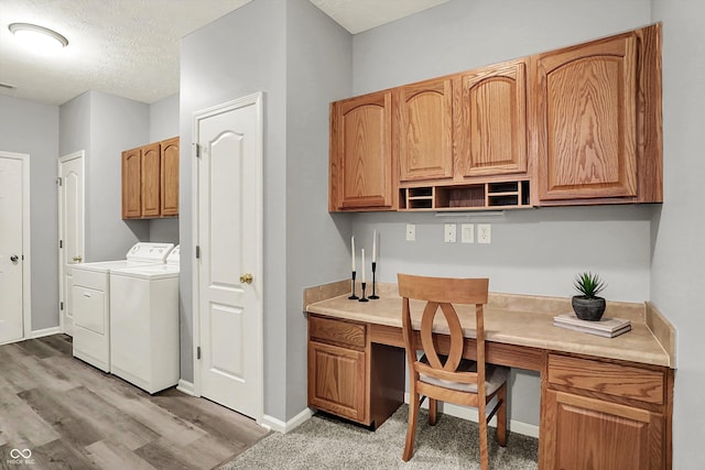 washroom with cabinet space, washer and dryer, light wood-style floors, a textured ceiling, and baseboards