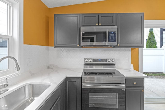 555 N Hamilton Ave, Indianapolis, IN 46201 - kitchen featuring light stone countertops, tasteful backsplash, appliances with stainless steel finishes, a sink, and vaulted ceiling