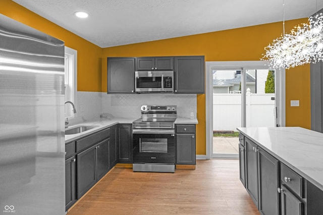 555 N Hamilton Ave, Indianapolis, IN 46201 - kitchen featuring light stone counters, a sink, lofted ceiling, light wood-type flooring, and stainless steel appliances