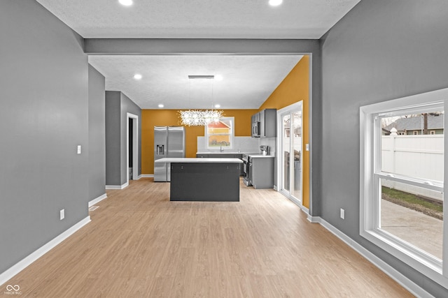 555 N Hamilton Ave, Indianapolis, IN 46201 - kitchen with light wood finished floors, a center island, stainless steel appliances, baseboards, and an inviting chandelier