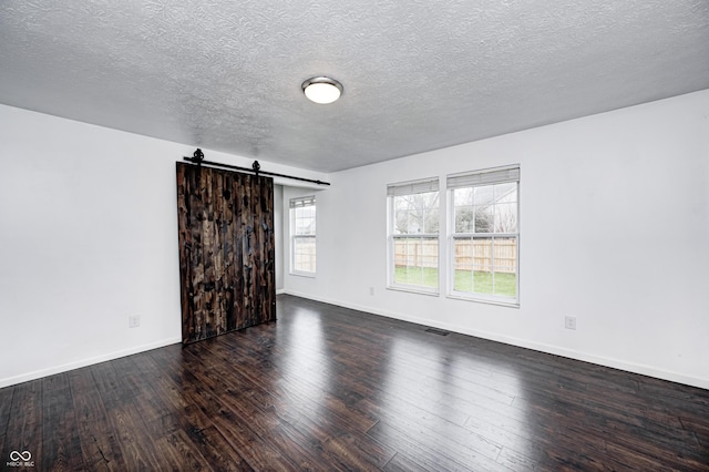 6036 Terrytown Pkwy, Indianapolis, IN 46254 - spare room featuring a barn door, a textured ceiling, baseboards, visible vents, and hardwood / wood-style floors