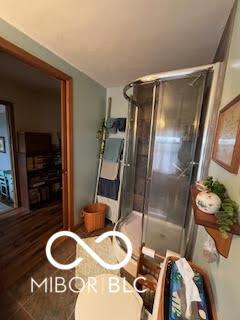 bathroom with toilet and a shower with door