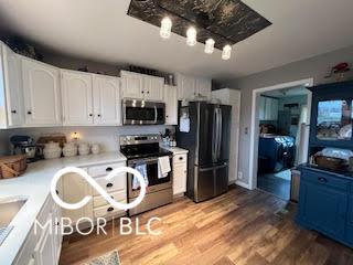 kitchen with wood finished floors, white cabinetry, stainless steel appliances, and light countertops