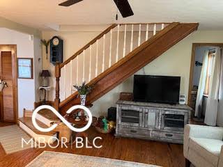 interior space with wood finished floors, a ceiling fan, and stairs