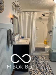 full bathroom with a textured ceiling, vanity, and shower / tub combo