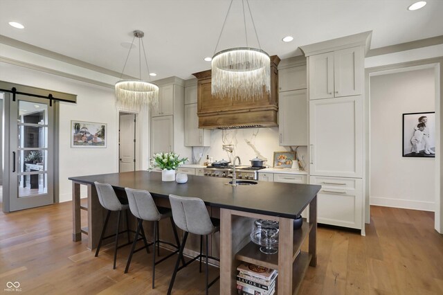 5130 Melbourne Pl, Zionsville, IN 46077 - kitchen featuring dark countertops, recessed lighting, a kitchen island with sink, tasteful backsplash, and wood finished floors
